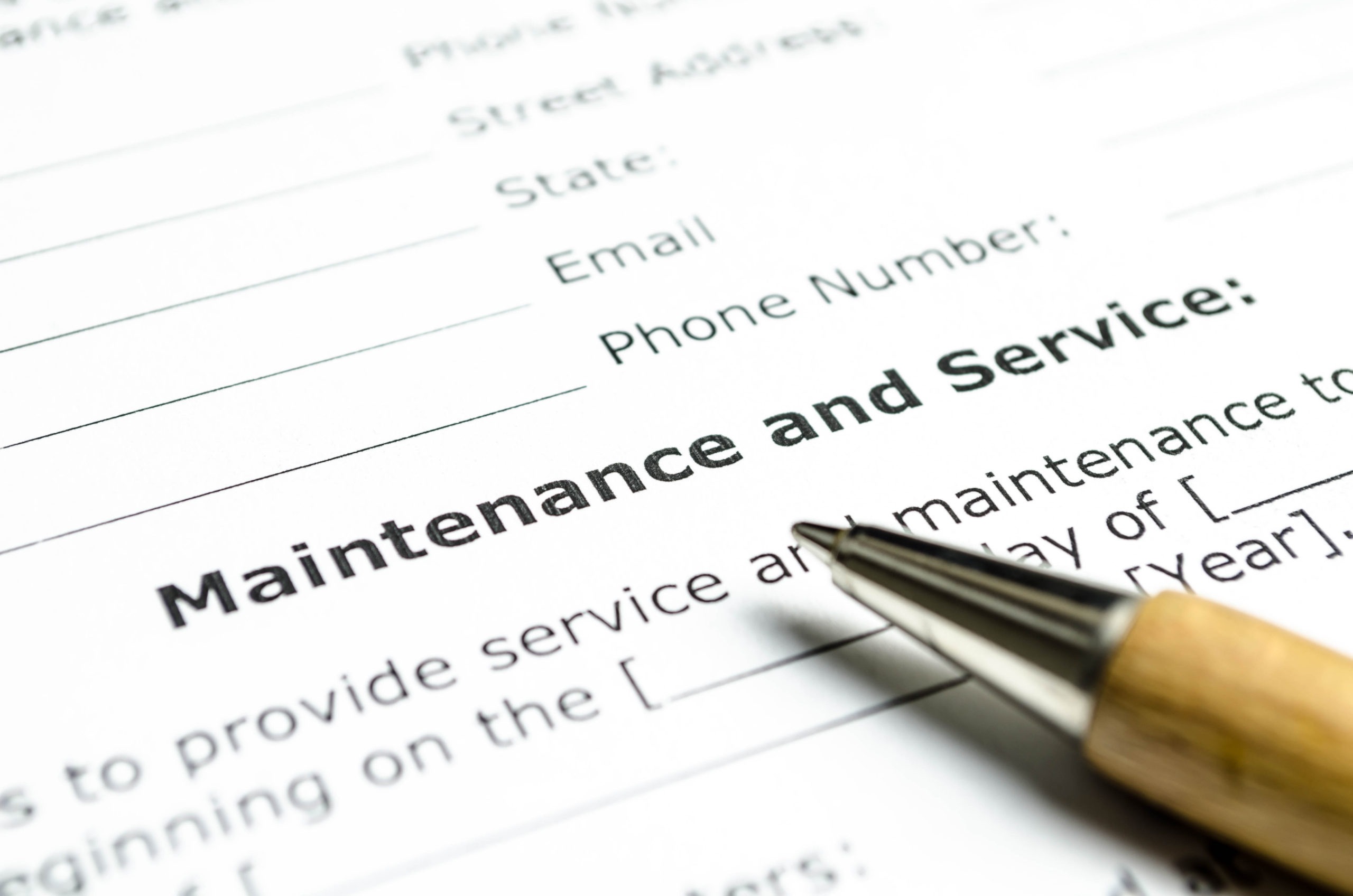 The image shows a close-up of a "Maintenance and Service" form with fields for personal information, accompanied by a metal pen.
