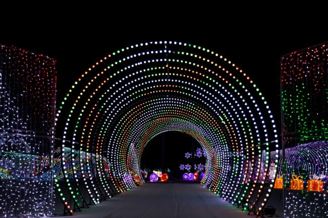 This image shows a vibrant, illuminated tunnel made of numerous colorful lights, creating a festive and mesmerizing atmosphere at nighttime.